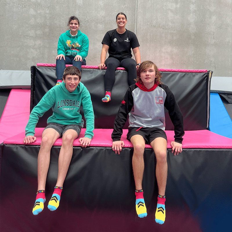 Four people sitting on crash mats at an activity centre.